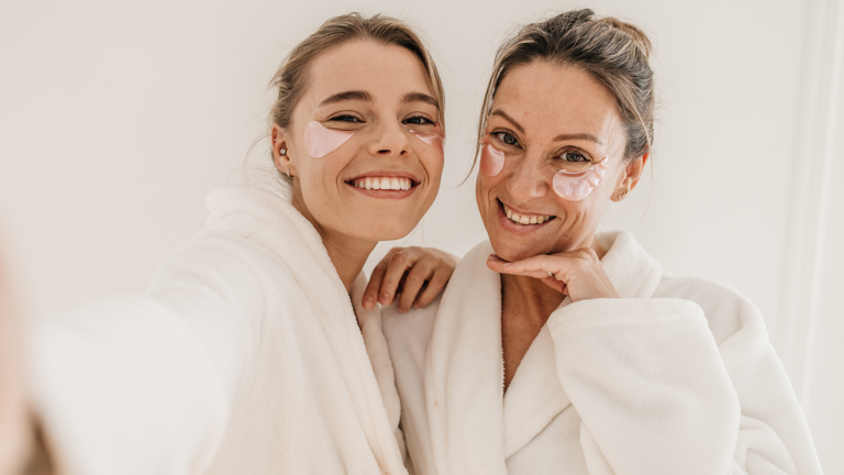 Happy Caucasian Women Use Eye Patches Wear Bathrobes Look Camera White Background Concept Preserving Youth